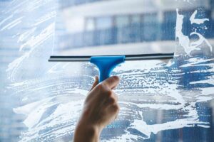 A professional cleaner meticulously wiping the interior side of a large glass window in Fort Lauderdale.