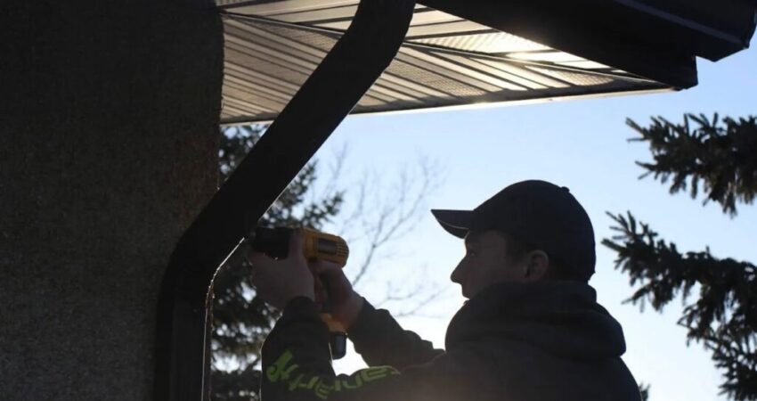 A technician performing emergency gutter repair on a home in Sarasota during heavy rain.