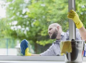 A professional window cleaner washing a large exterior window on a residential home in Cape Coral.