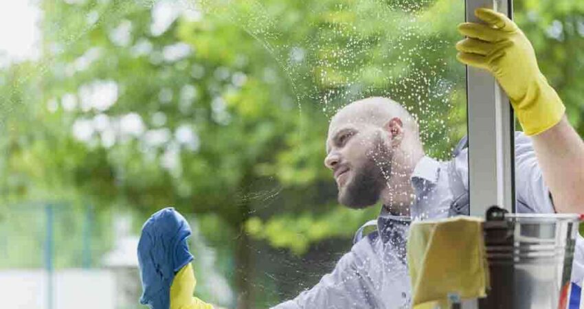 A professional window cleaner washing a large exterior window on a residential home in Cape Coral.