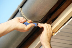 A professional repairing a leaking gutter on a Fort Lauderdale home.