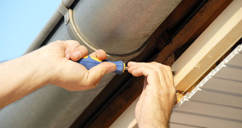 A professional repairing a leaking gutter on a Fort Lauderdale home.