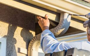 A technician repairing a sagging gutter on a Fort Lauderdale home.